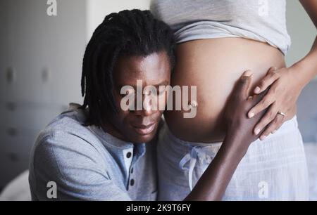 Prometto di essere il miglior papà, un uomo che ascolta il suo ventre incinta. Foto Stock