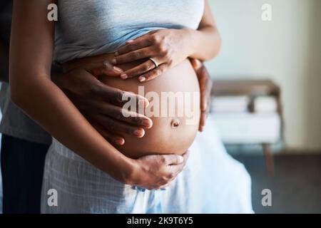 Un uomo irriconoscibile che tiene la sua incinta si sguadel ventre a casa. Foto Stock