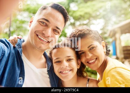 Theres sempre tempo per un selfie della famiglia. Ritratto ritagliato di una giovane famiglia di tre che scattano selfie nel parco. Foto Stock