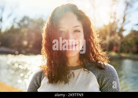 Stare all'aperto è sempre fantastico. Ritratto di una bella giovane donna in piedi accanto ad un lago. Foto Stock