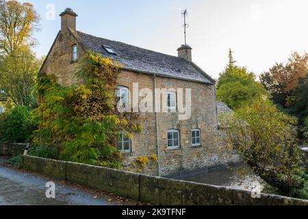 Cottage sul fiume windrush in autunno. Naunton. Cotswolds, Gloucestershire, Inghilterra Foto Stock