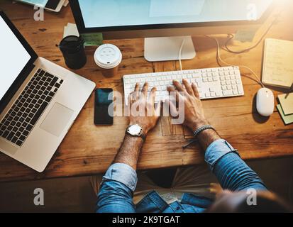 Scendere a ciò che deve essere fatto. Ripresa ad angolo alto ritagliato di un uomo d'affari che utilizza un computer durante una tarda notte al lavoro. Foto Stock