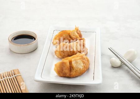 Gyoza, gnocchi fritti con pollo succoso e cavolo. Servito in piatto bianco con salsa di soia Foto Stock