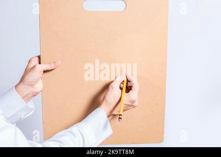 Primo piano delle mani del medico con la matita sopra gli appunti con lo spazio della copia. Il dottore scrive le mani su appunti di legno in bianco isolato. Concetto di mani Foto Stock