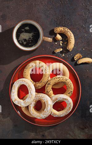 Vista ad angolo alto di vari bagel nella piastra rossa e tazza di caffè su una griglia da forno in metallo Foto Stock