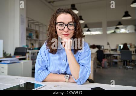 Donna d'affari giovane e sicura che guarda la webcam in ufficio, ritratto. Foto Stock