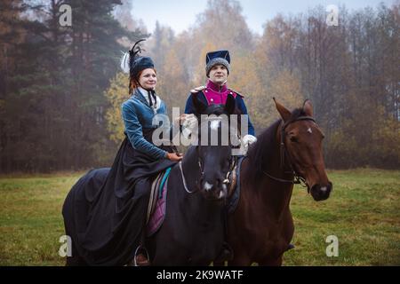 Uomo e donna in 19th ° secolo Empire costumi di stile posa a cavallo, uomo e donna tenendo le mani Foto Stock