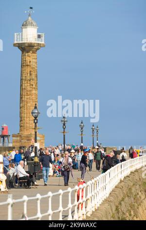 WHITBY, Regno Unito - 21 settembre 2022. I turisti camminano lungo il molo Whitby (muro del porto) con un faro sullo sfondo. Whitby, North Yorkshire, Regno Unito Foto Stock