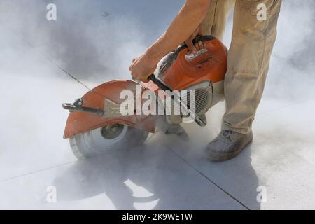 Le seghe a lama diamantata vengono utilizzate dai lavoratori edili per tagliare il marciapiede in cemento Foto Stock