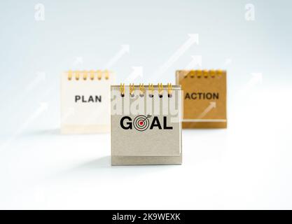 Business action, plan and goal, text and Icons on Small gray, beige and white desk calendar year 2023 standing with rise up arrows on white background Foto Stock