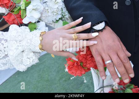 Mani di sposi novelli con anelli di nozze e bouquet nuziale. Foto Stock