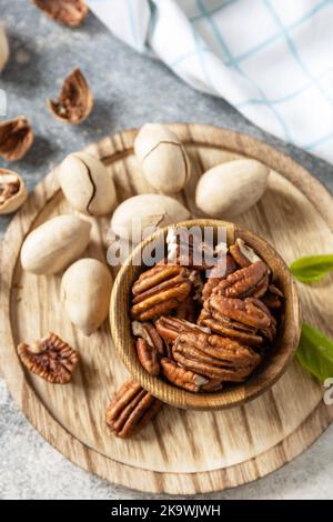 Ciotola con noci pecan su un tavolo di pietra. Noci e semi, grassi sani, vari oligoelementi e vitamine. Foto Stock