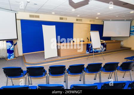 Zona meeting in ufficio in stile loft con pareti in mattoni bianchi e colonne in cemento. La zona ha un grande tavolo in legno con sedie grigie e parti in vetro Foto Stock