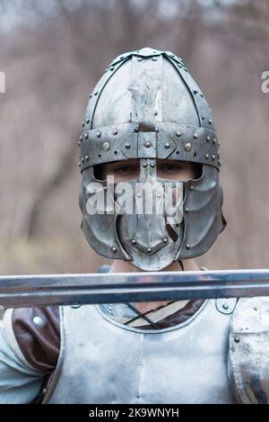 Nobile guerriero. Ritratto di un guerriero o cavaliere medeivale in armatura e casco con scudo e spada in posa isolata su sfondo scuro. Foto Stock