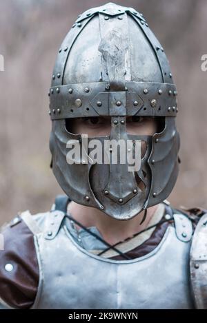 Nobile guerriero. Ritratto di un guerriero o cavaliere medeivale in armatura e casco con scudo e spada in posa isolata su sfondo scuro. Foto Stock