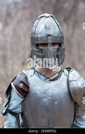 Nobile guerriero. Ritratto di un guerriero o cavaliere medeivale in armatura e casco con scudo e spada in posa isolata su sfondo scuro. Foto Stock