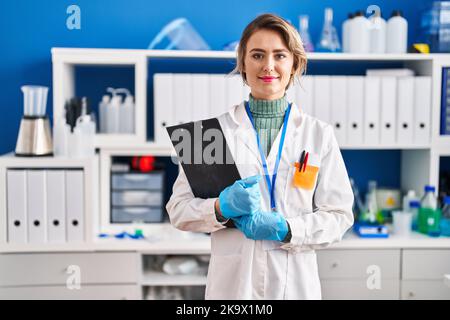 Giovane scienziata donna che accoccolano gli appunti in laboratorio Foto Stock