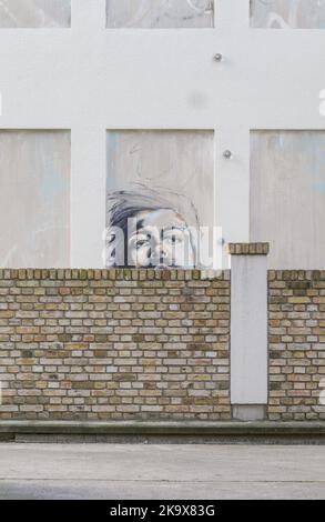 Ritratto di street art su muro rivestito, cortile di Berlino, Germania, murale urbano nascosto dietro un muro di mattoni Foto Stock
