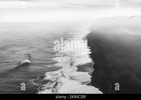 Nebbia mattutina e nuvole sopra l'infinita spiaggia di sabbia nera a Dyrholaey, Islanda Foto Stock