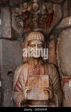 Primo martire cristiano, Santo Stefano, si trova sotto una capitale romanica scolpita che mostra una folla che accumula pietre e rocce per gettarlo contro di lui. Austere 12th ° secolo colonna statua nel portale nord della Basilique Saint-Just, consacrata nel 1200 a Valcabrère in Occitanie, sud-ovest della Francia. Foto Stock