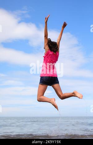 contenta ragazza saltando e gioendo felice dal mare in estate Foto Stock