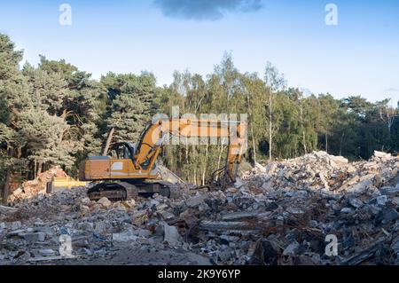 Processo di demolizione di un vecchio edificio. Rottura dell'escavatore. Distruzione di alloggi fatiscenti per un nuovo sviluppo Foto Stock