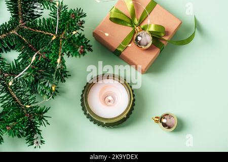 Sfondo di Natale con candela, scatola regalo, rami di abete e giocattoli di Natale su tavolo verde. Vista dall'alto, disposizione piatta. Foto Stock