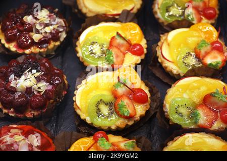 Torte con frutta fresca e frutti di bosco, focus selettivo. Dolce con fragole, pesche, kiwi e ciliegia Foto Stock