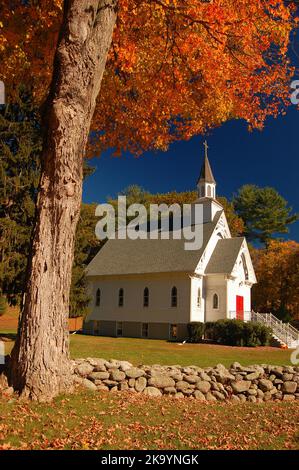 La piccola cappella della chiesa di St Bridget è incorniciata da un muro di pietra e da un brillante e colorato fogliame autunnale in una classica scena autunnale del New England Foto Stock