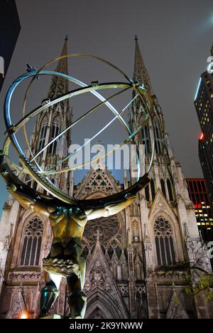 Una scultura di Atlante nel Rockefeller Center si erge forte di fronte alla Cattedrale di San Patrizio, New York Foto Stock
