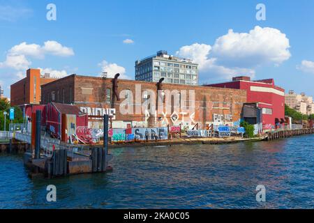 Graffiti lungo l'East River Waterfront sotto un edificio di loft a Brooklyn, New York, USA. Foto Stock