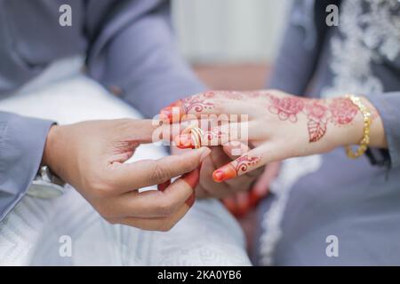 Lo sposo ha messo un anello di nozze sulla mano della sposa Foto Stock