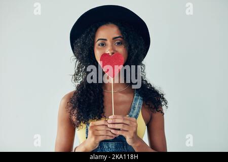 Ama solo l'amore e tutto ciò che rappresenta. Studio di una giovane donna attraente che posa su uno sfondo grigio. Foto Stock