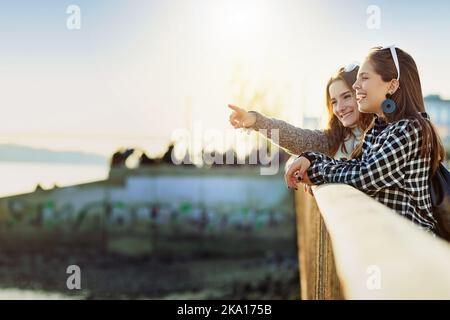 Se guardate quello. Una giovane donna attraente che indica qualcosa alla sua amica mentre sta in piedi su un punto di osservazione. Foto Stock