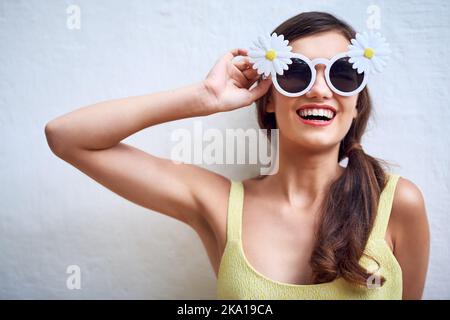 Io sono più di quello che vedi. Studio ritratto di una giovane donna allegra indossare occhiali da sole mentre si posa su uno sfondo grigio. Foto Stock