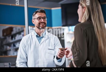 Grazie. Sarà tutto questo. Una giovane donna che paga merce con una carta di credito in farmacia. Foto Stock