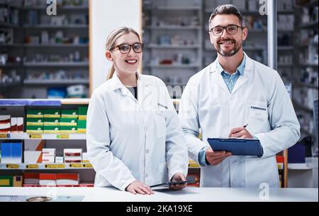Qui per aiutarvi a mantenervi nella vostra salute migliore. Ritratto di due farmacisti che lavorano in farmacia. Foto Stock