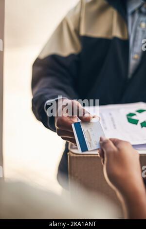 Utilizzare il corriere è diventato più comodo. Primo piano di un corriere che accetta il pagamento con carta di credito da parte di un cliente per una consegna. Foto Stock