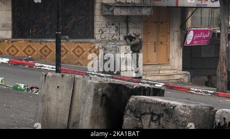 Un soldato israeliano punta la sua arma durante gli scontri con i soldati palestinesi nel quartiere palestinese di Bab a-Zawiya il 30 ottobre 2022 a Hebron, Israele. Foto Stock