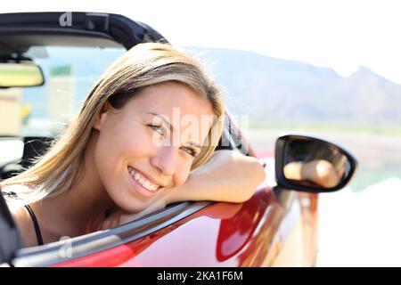 Felice conducente di auto convertibile sorridente e riposante guardando via Foto Stock