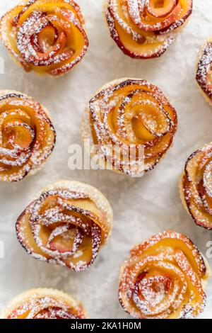 Torte di mele al forno in forma di rose con cannella e chiodi di garofano su una teglia da forno Foto Stock