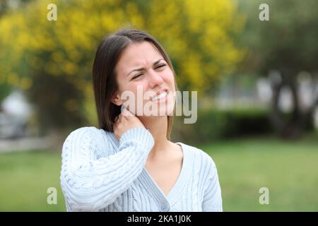 Stressato teen dolore al collo in un parco Foto Stock