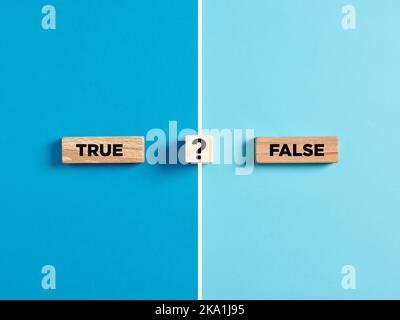 Le parole vero e falso su blocchi di legno con il simbolo del punto interrogativo. Dilemma o scelta tra la verità e le opzioni di informazione falso. Foto Stock