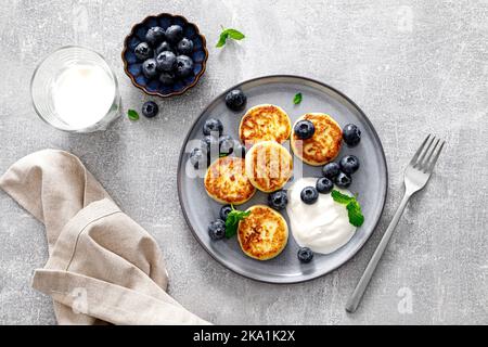 Frittelle di formaggio caserma con mirtillo fresco e yogurt per colazione, spazio copia, vista dall'alto Foto Stock