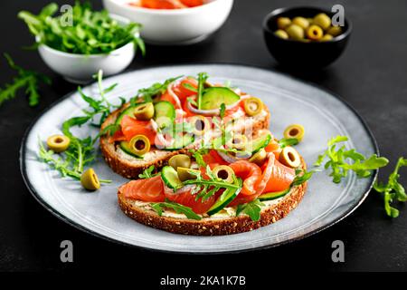 Tostatura con salmone salato, rucola, olive verdi e cetriolo Foto Stock