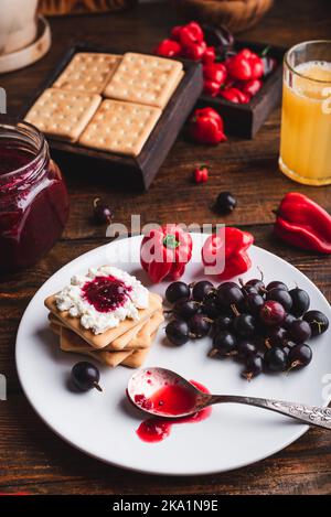 Confettura di uva spina e pepe rosso Habanero con formaggio cremoso sui cracker Foto Stock