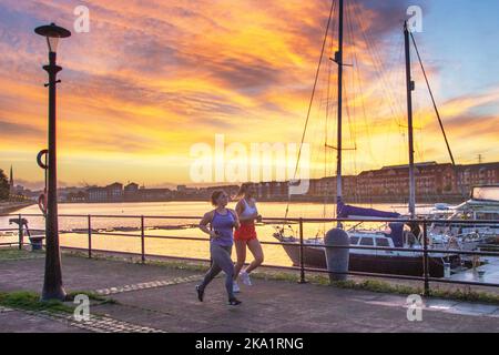 Preston. UK Weather, 31 Ott 2022. Un caldo inizio di sole alla giornata nel nord-ovest come il sole sorge sopra Preston Docks. Le temperature miti continuano mentre i residenti locali godono di una leggera attività fisica lungo il Riverside Walk, parte della Navigation Way nei Docklands. Credit; MediaWorldImages/AlamyLiveNews Foto Stock