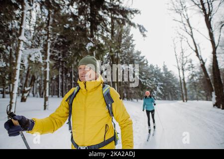 Coppia anziana sciare insieme nel mezzo della foresta Foto Stock