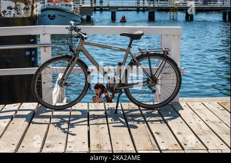 Ein Fahrrad auf der Seegartebrücke in Kiel, eine junge Frau telefoniert Foto Stock