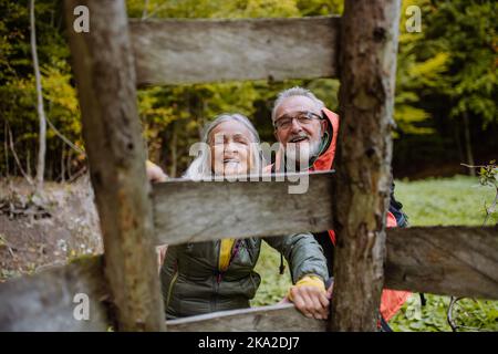 Felice coppia di anziani che si arrampica a caccia alto sedile nella foresta autunnale. Foto Stock